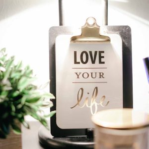 Faith & Purpose Circle A warmly lit desk setup featuring a lamp, inspirational clipboard, and decor for a cozy ambiance.